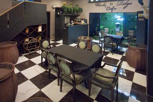 a dining room with a table and chairs on a checkered floor at Windy Ridge Hotel Malate Manila in Manila