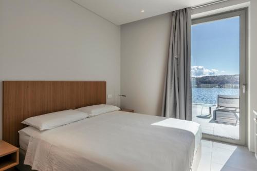 a bedroom with a bed and a large window at Villa Acquariva Private Heated Pool in Salò