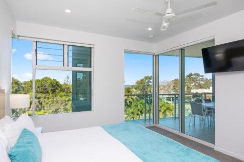 a bedroom with a bed and a tv and sliding glass doors at Akama Resort in Hervey Bay