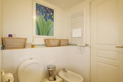 a white bathroom with a toilet and a sink at Le Studio des Deux Frontières in Beausoleil