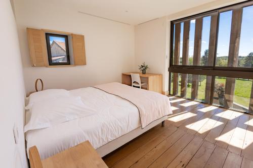 a bedroom with a bed and a large window at Maison Lotus - Groupes et familles, séjour Nature au coeur du Périgord Vert in Saint-Martial-de-Valette