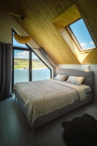 a bedroom with a large bed with a large window at Gródek & Ogródek in Gródek Nad Dunajcem