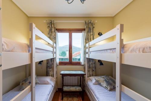 a room with two bunk beds and a window at Las Camelias in Argoños