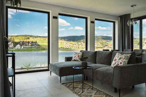 a living room with a couch and large windows at Gródek & Ogródek in Gródek Nad Dunajcem