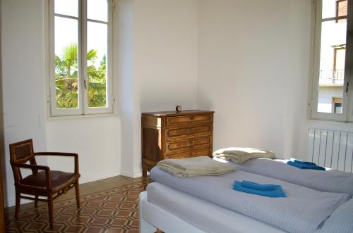 a bedroom with a bed and a chair and windows at Casa Corten, Vista Lago in Cerro Lago Maggiore
