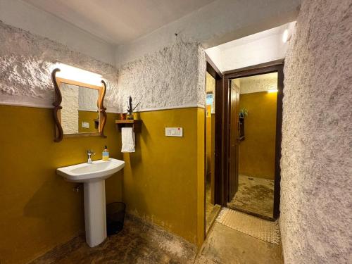 a bathroom with a sink and a yellow wall at T Stop Farmhouse Coorg in Kurchi