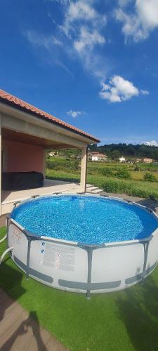 a large pool sitting in the grass next to a house at Just Like Home - Casa Rosa in Padornelo