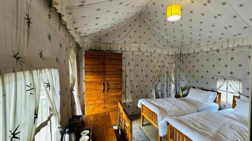 ein Schlafzimmer mit zwei Betten in einem Zelt in der Unterkunft Escape Pod Himalayan Campsite in Bhīm Tāl