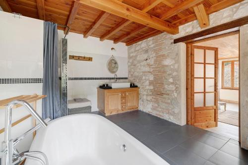 a bathroom with a bath tub and a stone wall at Chambres D'hôtes La Boriette in Castelnau-de-Montmiral