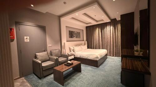a bedroom with a bed and a couch and a chair at Clowzer Hotel- فندق كلاوزر in Riyadh