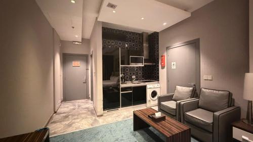 a living room with a couch and a chair and a kitchen at Clowzer Hotel- فندق كلاوزر in Riyadh