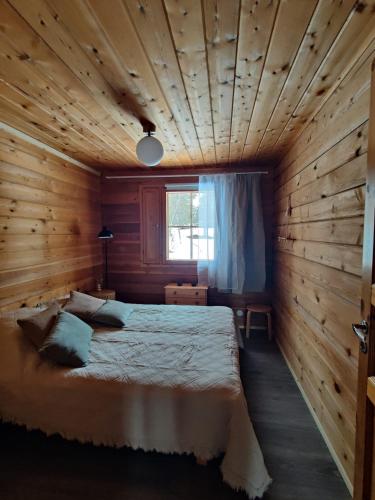 ein Schlafzimmer mit einem Bett in einem Holzzimmer in der Unterkunft Metsäkoti in Saariselkä