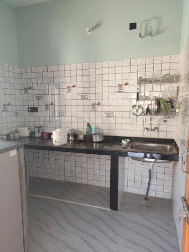 a kitchen with a sink and a tiled wall at Rawat ji Homestay in Rāmnagar