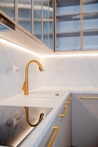 a kitchen with a sink and gold faucet at Galant Apartments in Cluj-Napoca
