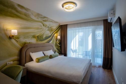 a bedroom with a bed with a painting on the wall at Galant Apartments in Cluj-Napoca