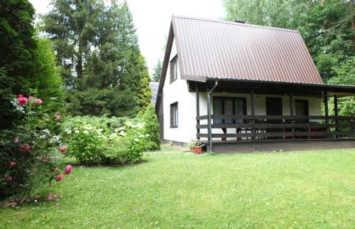 a white house with a red roof and a yard at Domek Mazury u Basi in Jerutki