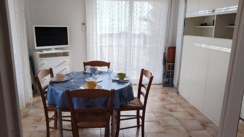 a dining room with a table and chairs and a television at Appartement balcon proche mer in Saint Pierre La Mer