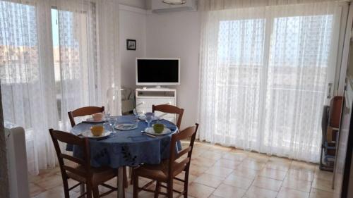 a dining room with a table with chairs and a television at Appartement balcon proche mer in Saint Pierre La Mer