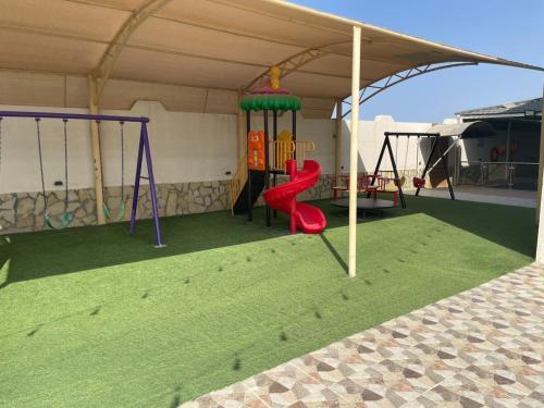 a playground in a tent with a slide and swings at استراحة العمران in Murayjāt