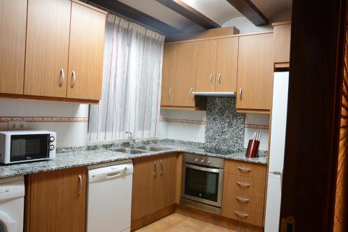 a kitchen with wooden cabinets and a sink and a microwave at Casa Domingo in Manzanera