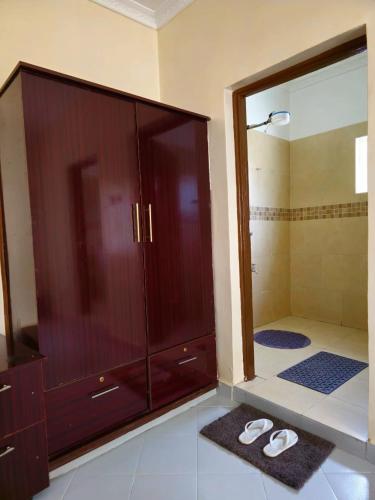 a bathroom with a large wooden cabinet and two slippers at Larami House Narok in Narok