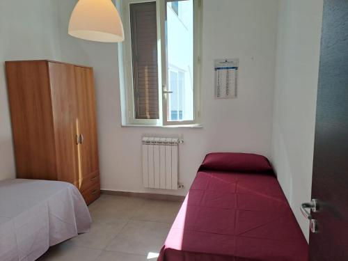 a bedroom with a red bed and a window at Medoro Gioiosa 2 in Gioiosa Marea