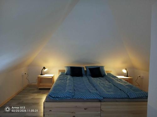 a bedroom with a bed with blue sheets and two lamps at Pehely Vendégház in Lesencetomaj