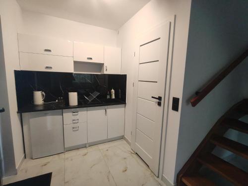 a kitchen with white cabinets and a black counter top at Apartament Skorochów Jezioro in Skorochow