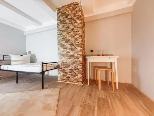 a room with a bed and a table and a brick wall at Drei Linden Rosenwall in Wolfenbüttel