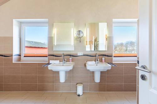 a bathroom with two sinks and two mirrors at Ferienhaus Nordspitze in Dagebüll