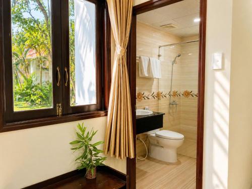 a bathroom with a toilet and a shower with a window at Cửu Long Beach Phú Quốc in Phú Quốc