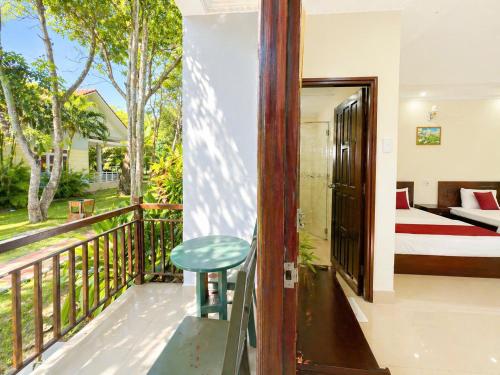 a room with a balcony with a bed and a table at Cửu Long Beach Phú Quốc in Phú Quốc
