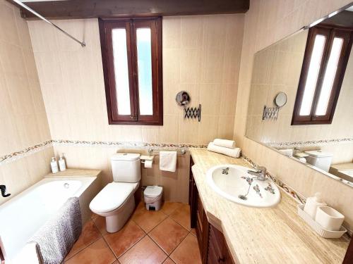 a bathroom with a toilet and a tub and a sink at Sa Màniga in Fornalutx