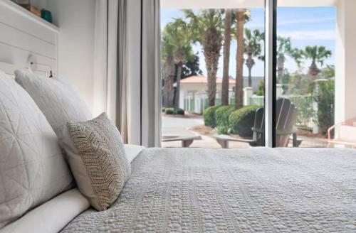 a white bed with pillows in front of a window at Bluehavenon30a-Between Rosemary & Alys Beach -Steps to Beach & Dining-Sleeps 3 in Rosemary Beach