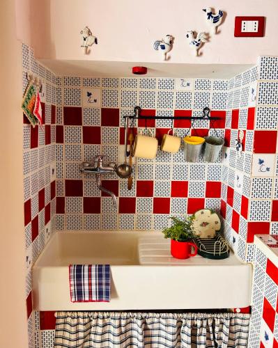 a kitchen sink with a red and white tiled wall at Il balconcino di Riamori in Amelia
