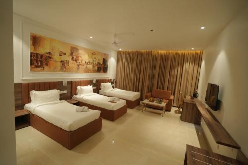 a bedroom with two beds and a couch and a tv at The Grand Icon in Chandrapur