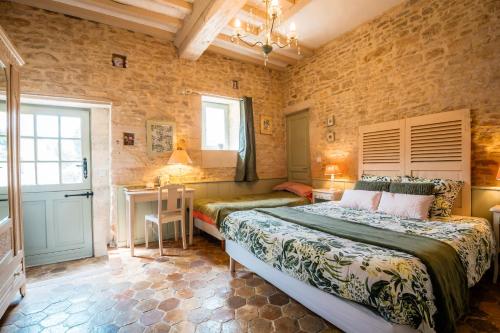 a bedroom with two beds and a table and a desk at Le chant des oiseaux in Ryes