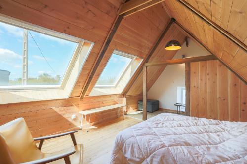 an attic bedroom with a bed and two windows at Gite des Hauts Grève - Penty in Saint-Michel-en-Grève