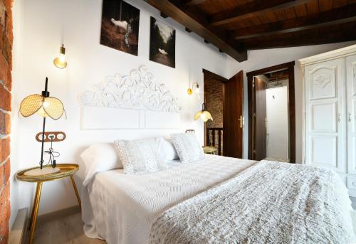 a bedroom with a white bed and a table at Apartamentos La Cabaña del Cerro Alto in Beceña