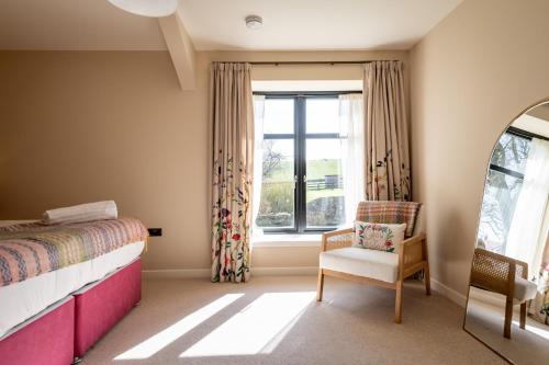 a bedroom with a bed and a chair and a window at Easter Kincaple Garden Cottage in St. Andrews
