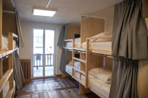 a room with several bunk beds with a window at BodyGo Hostel Briançon in Briançon