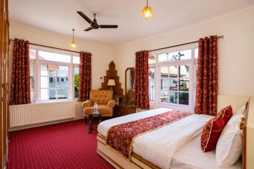 a bedroom with a bed and a chair and windows at Dar-e-Shafi in Srinagar