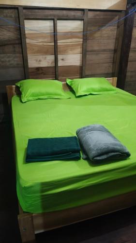 a green bed with two pillows on top of it at GoodMuning SurfCamp in Taliwang
