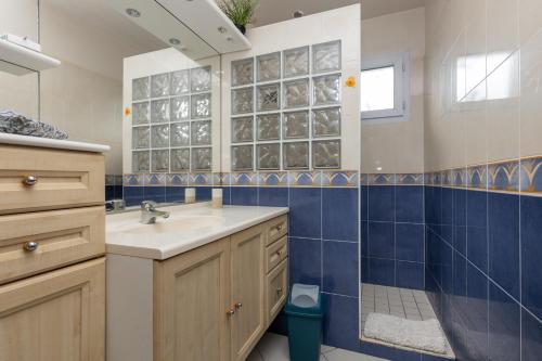a bathroom with a sink and a blue tiled wall at Belle Maison Basque à Bardos Clim in Bardos