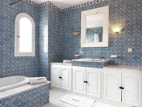 a blue bathroom with a tub and a sink at Villa Oasis Hammamet in Hammamet
