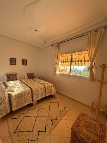 a bedroom with a bed and a window and a rug at Apartment with pool next to the ocean in Agadir nʼ Aït Sa