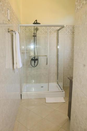 a shower with a glass door in a bathroom at Residence Six Sigma in Entebbe