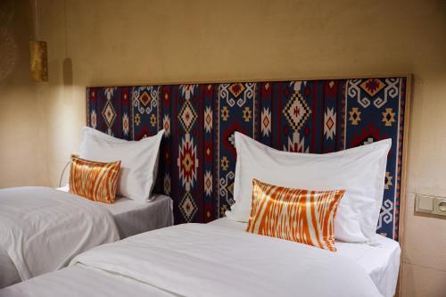 two beds with white sheets and orange pillows at Hotel Old Heritage in Tashkent