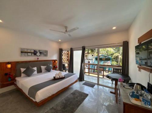 a bedroom with a large bed and a balcony at White Turtle Resort in Morjim