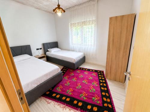 a bedroom with two beds and a red rug at Versailles Rooms in Dukati i Ri